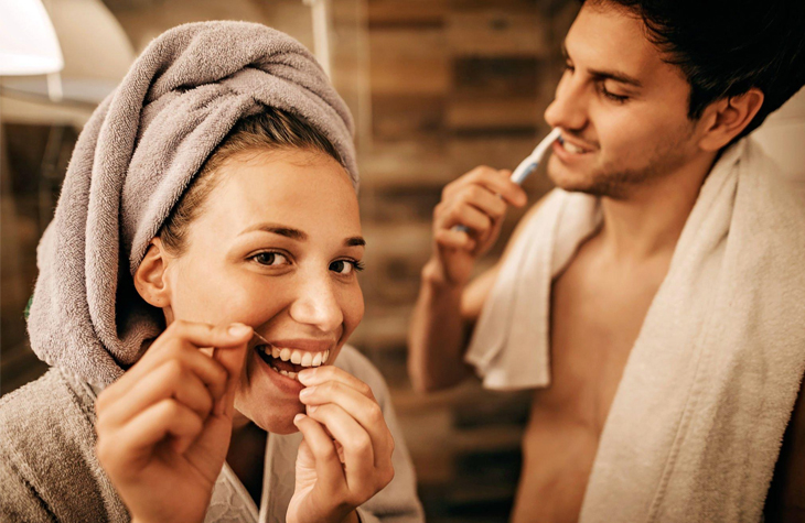 Father and child brushing teeth together in bathroom, promoting family dental hygiene and care.