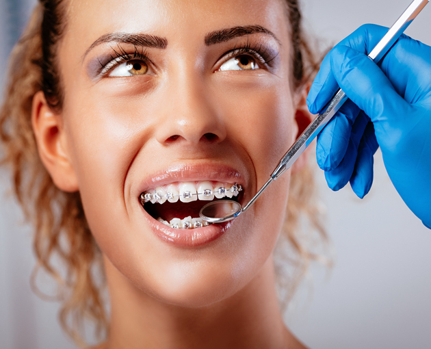 Woman smiling during dental examination with dentist holding mirror tool in clinical setting.