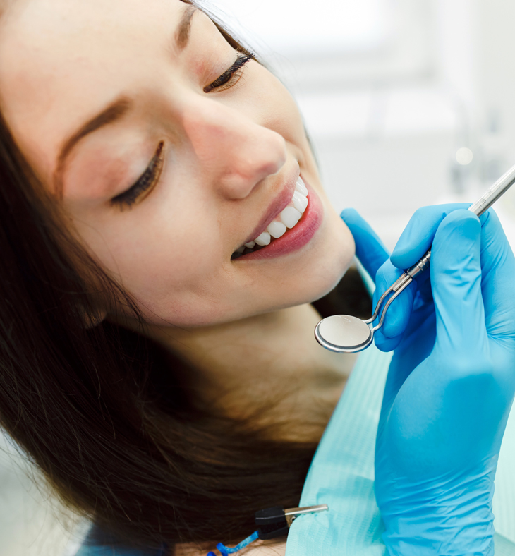 Woman smiling during dental examination with dentist in blue gloves at dental office