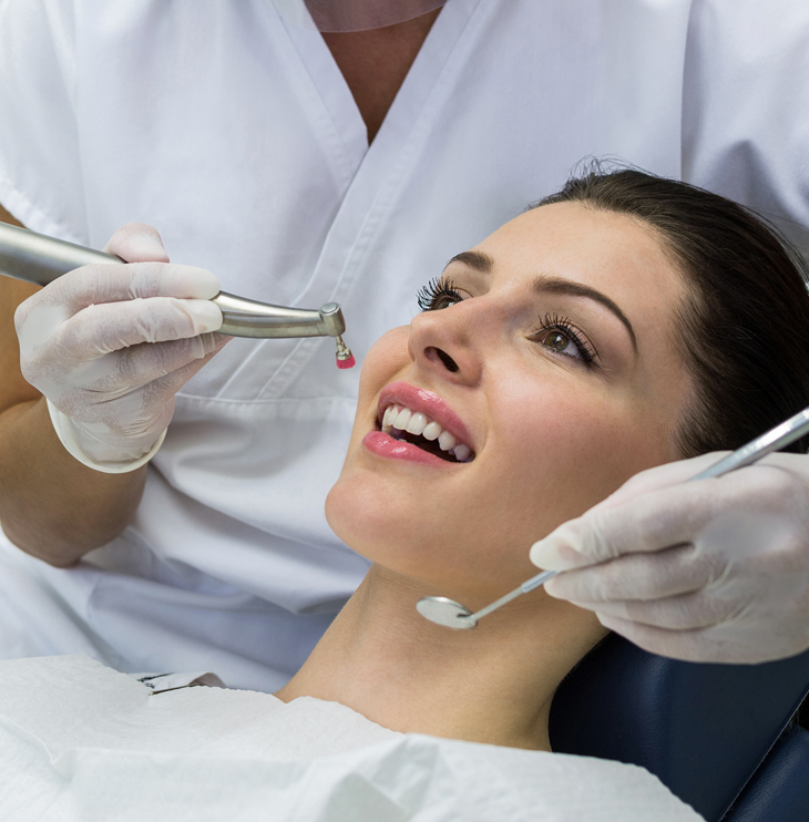 Dentist examining smiling patient's teeth during dental checkup at Austin Park Dental clinic.