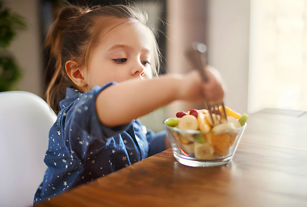 Young child reaching for french fries at table indoors.