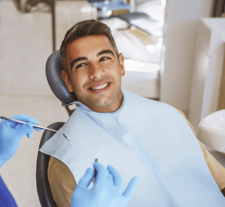Smiling male patient in dental chair wearing bib at Austin Park Dental office.