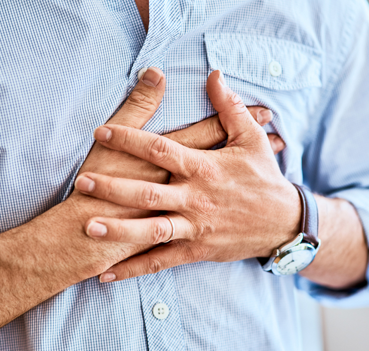 Man holding chest in light blue shirt, experiencing discomfort or pain