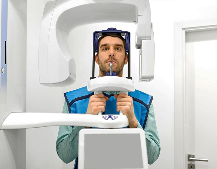 Man positioned inside dental imaging scanner equipment at modern dental clinic.