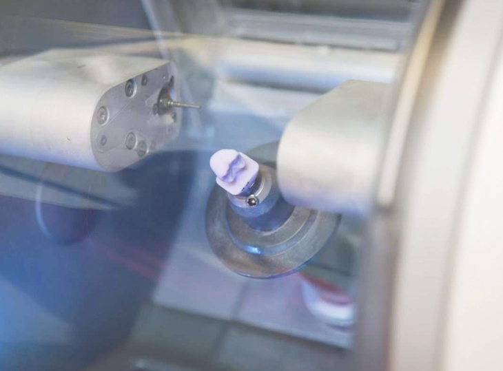 Dental water bottle or rinse cup displayed in clear acrylic holder on dental office counter.